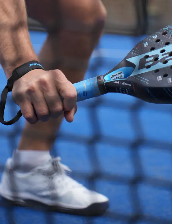 Bold overgrip on premium padel racket behind net